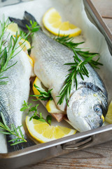 Fresh raw dorado fish with lemon, rosemary on kitchen table