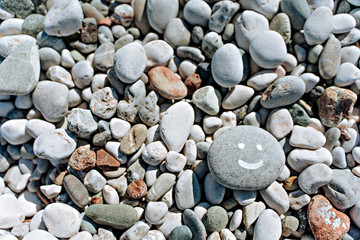 stones on the beach with a blue sea and the inscription smile