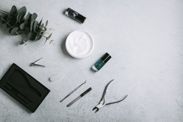 Nail polish, manicure tools and hand cream on grey concrete table top flat lay. How to do manicure at home concept. Do manicure by yourself while staying at home during quarantine, staying safe