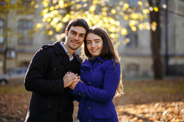 guy with a girl cuddling against a background of yellow foliage. Autumn in the park. sunny day