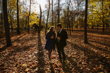 Fototapeta premium guy with a girl drink coffee in a park. Autumn in the park. sunny day