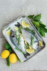 Fresh raw dorado fish with lemon, rosemary on kitchen table
