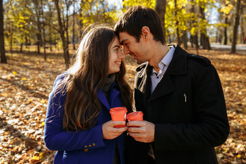 guy with a girl drink coffee in a park. Autumn in the park. sunny day