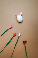 easter bunny made from chikern egg with wooden flowers on craft paper background, sping at home and easter at home concept