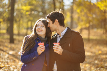 guy with a girl drink coffee in a park. Autumn in the park. sunny day