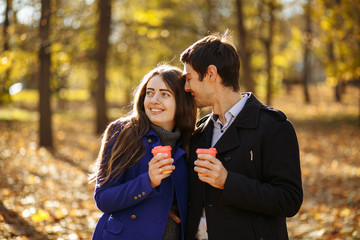 guy with a girl drink coffee in a park. Autumn in the park. sunny day