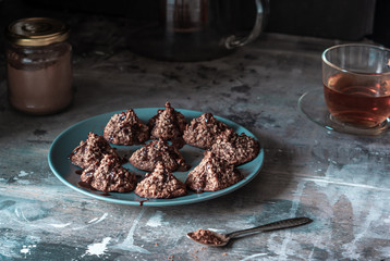 Homemade coconut cookies with cocoa, on a gray plate and shabby wooden background. Dark food photo.