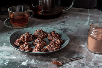 Homemade coconut cookies with cocoa, on a gray plate and shabby wooden background. Dark food photo.
