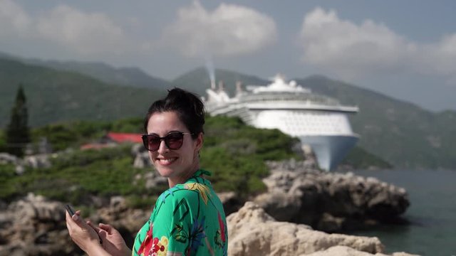 Young woman tourist takes picture of docked cruise ship in caribbean
