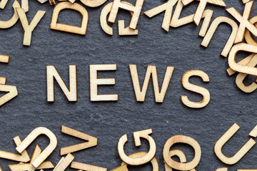 wooden letters NEWS on slate background