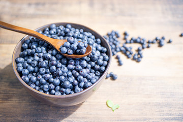 Fresh blueberries in a bowl on a wooden surface, closeup