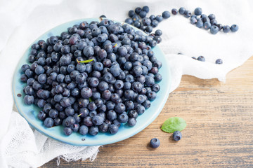 Fresh blueberries in a blue bowl on a wooden surface, closeup