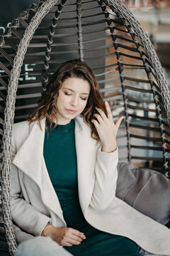 Beautiful young brunette girl sitting in a restaurant at the table posing to the camera