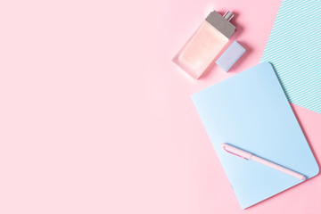 Flat lay female workplace. Notebook, pen and perfume on a pink background. The design of the blog and social networks