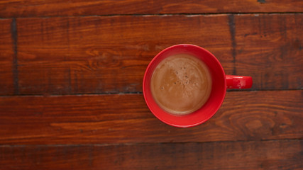 Taza roja de café sobre una mesa de madera.