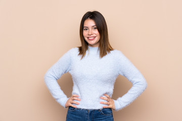 Young woman over isolated background posing with arms at hip and smiling