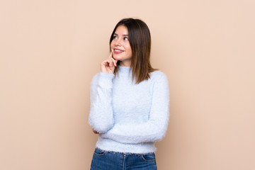 Young woman over isolated background thinking an idea while looking up