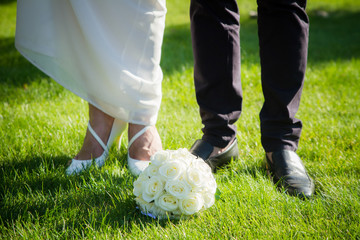 Wedding bouquet of the bride and feet newlyweds