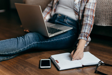 woman keep laptop and write at note book on brown wooden background. 