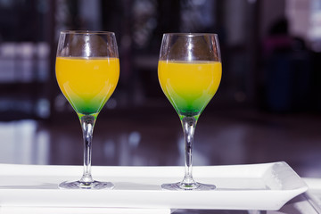 Two glasses of cocktail on a white porcelain plate in a bar