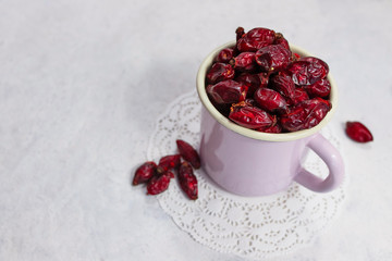 Dried rose hips in enameled mug top view on white background
