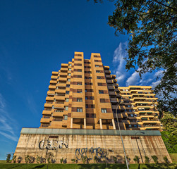 high building in the city with graffiti on the base and very blue sky