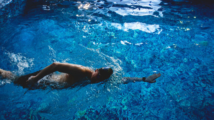 Professional male swimmer crawls underwater in a blue swimming pool