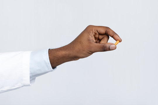 Close up of black doctor hand holding one single pill
