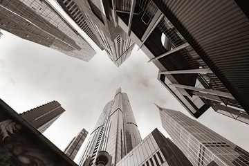 Low point of view from street looking upward through high-rise buildings with converging perspective.
