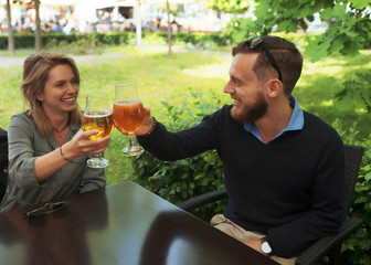 Smiling young brother and sister clinking their glasses of beer