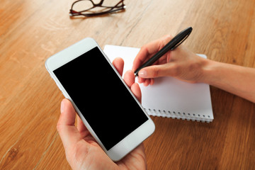 female hands holding smart phone on wooden background  , place for your text