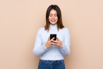 Young woman over isolated background sending a message with the mobile