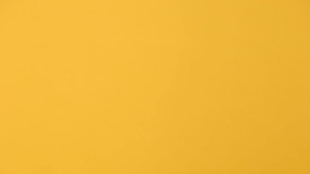 Close up male hold give hand in sterile black glove brown clear empty blank craft paper bag for takeaway isolated on yellow background. Packaging template mockup. Delivery service concept. Copy space