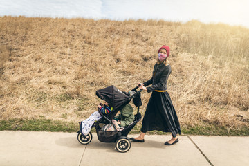Mother walking her boys through the park in Chicago during quarantine wearing face masks
