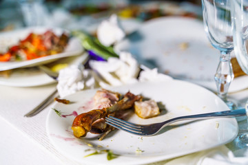 The leftover food and dirty dishes on the restaurant table. Scraps left over after the party.