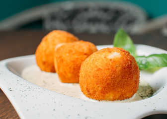 Beef Arancini on restaurant table with 4 cheese sauce