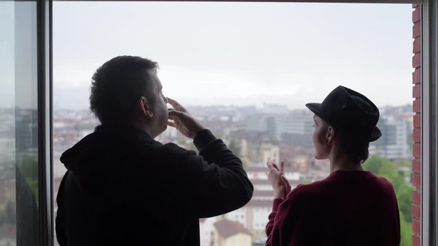 Young couple in Spain applaud and whistle from their window in recognition and support of public health officials who fight against the coronavirus. they raise their fist as a sign of resistance again