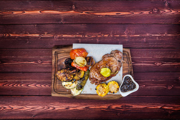 Delicious grilled steak with assorted roast vegetables and corn with sauce. Top view