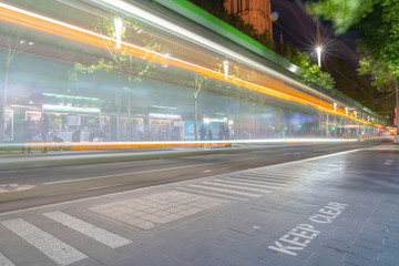 Blurred image of city tram whizzing past keep clear sign on pavement