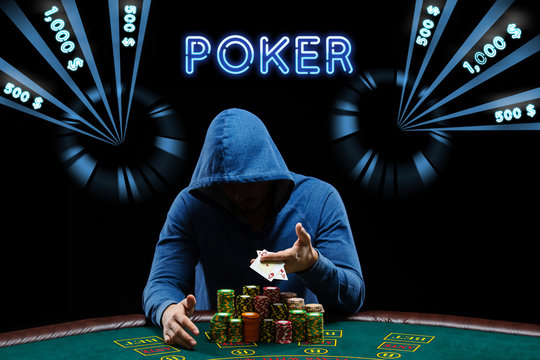 Man in blue hoodie showing aces, sitting at playing table with stacks of chips. Black background with neon dollar amounts, inscription poker. Casino