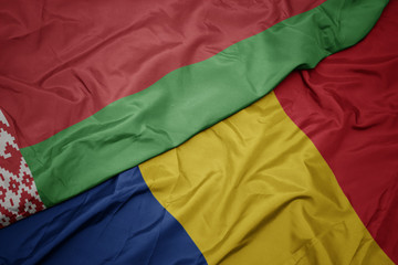 waving colorful flag of romania and national flag of belarus.