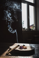 Burning stick palo santo creating smoke with crystals on wooden plate. Energy healing, cleansing and purification indoor. Great for the practicing yoga and meditation. 