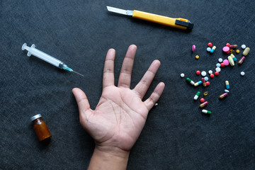 Close up of man hand on table with pills and syringe, drug abuse 