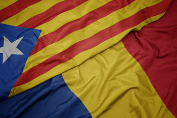 waving colorful flag of romania and national flag of catalonia.