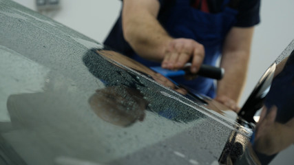 Close up of paint protection film installation on modern luxury car. PPF is polyurethane film that wrap car paint to protect paint surface from stone chips, bug splatter, and abrasion.