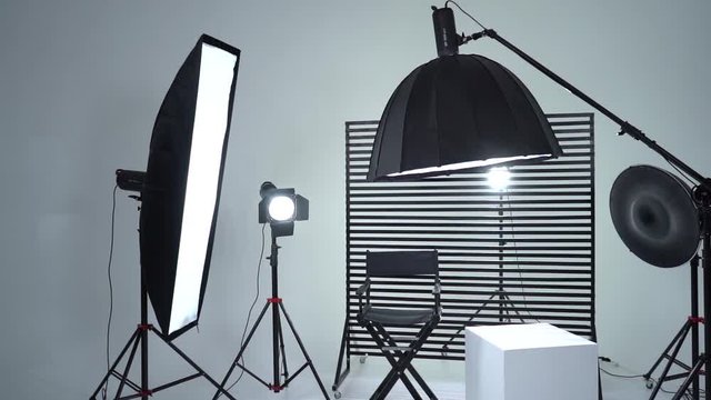 Crystal White room cyclorama. Modern photo studio with professional equipment. Empty photo studio with lighting equipment. Interior of modern photo studio with director production chair.