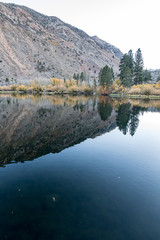 Fototapeta na wymiar reflecctive mountain lake with pines aspens grass and mountain