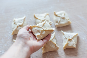 Fototapeta na wymiar Modeling envelopes from dough with filling. Homemade baking.