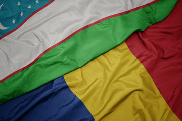 waving colorful flag of romania and national flag of uzbekistan.