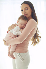 Beautiful woman with a baby is resting in a cozy house.